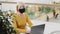 Mature woman professional worker freelancer in protective mask sitting in workplace typing on laptop modern middle aged