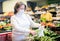 Mature woman in protective mask choice beans on grocery store shelves