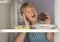 Mature woman reaching for chocolate cake inside fridge