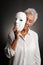 Mature woman revaling sad face behind mask