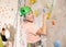 Mature woman in safety gear doing difficult wall climb in climbing gym