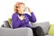 Mature woman seated on a sofa taking asthma treatment with inhaler