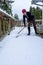 Mature woman shoveling fresh wet snow off a cedar deck, snow day