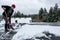 Mature woman shoveling fresh wet snow off a flat carport roof