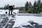 Mature woman shoveling fresh wet snow off a flat carport roof