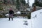 Mature woman shoveling fresh wet snow off a flat carport roof