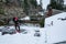 Mature woman shoveling fresh wet snow off a flat carport roof