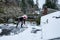 Mature woman shoveling fresh wet snow off a flat carport roof