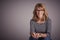 Mature woman sitting against at isolated grey background while looking at camera and laughing