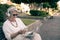 Mature woman sitting outdoor in public park using laptop computer and mobile phone. Nomadic blogger people, worker, businesswoman