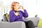 Mature woman on a sofa taking asthma treatment with inhaler at h
