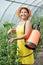 Mature woman spraying tomato plant