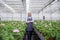 Mature woman standing in greenhouse near plants