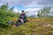 Mature woman takes rest pause, enjoying rare mountain Sun, holding water bottle and sandwiches in plastic pack, hiking high in