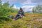 Mature woman takes rest pause, going to open water bottle , hiking high in Norwegian mountains. Healthy lifestyle. Norway,