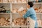 Mature woman taking clay jug from shelf while standing in workshop