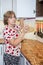 Mature woman taking glass volume with dry pasta on the shelve of food cupboard on the kitchen