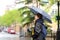 Mature woman tourist with umbrella walking on street of Manhattan in cool rainy spring day. Changeable weather New York