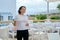 Mature woman walking with cup of coffee in outdoor restaurant resort hotel