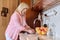 Mature woman washing apples at home in the kitchen