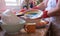 Mature woman washing crockery and cutlery in front to the window wearing red gloves