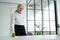 Mature woman wipes a wooden table with a rag. Elderly woman smiling and wipe away dust