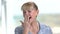 Mature woman is yawning on blurred background.