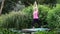 Mature woman in yoga position on wooden jetty by lake