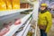 Mature women standing in a store by the shelves with canned goods