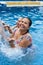 mature women with wet hair and bikini under the water jet in the swimming pool