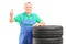 A mature worker posing on car tires and giving thumb up