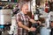 Mature workman sewing leather boots on stitch lathe