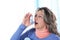 Matured woman inhales asthma spray