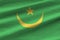 Mauritania flag with big folds waving close up under the studio light indoors. The official symbols and colors in banner