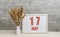 may 17. 17th day of month, calendar date. White vase with ikebana and photo frame with numbers on desktop, opposite