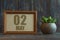 may 2nd. Day 2 of month, date in frame next to succulent on wooden background spring month, day of the year concept