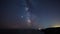 Mazing time lapse with Milky Way galaxy and plane trails at a rocky coastline