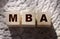 MBA master of business administration concept. Abbreviation inscription on wooden cubes standing on on a crochet carpet