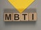 MBTI acronym on wood cubes on gray and yellow background. Psychological test