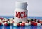 MCL - medical acronym on a white jar against the background of randomly scattered tablets