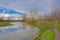 Meadow and lake with reflection of bare trees and reed in the flemish countryside