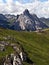 Meadow with rocks, hiking trail, Rifugio Sass Bece with Colac and other peaks in Dolomites