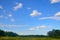 Meadow and sky. Blue sky with clouds. Skyline. View of the meadow and forest