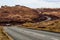 Meandering asphalt road traversing the arid brown hills of the Isle of Skye, Scotland, UK