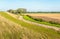 Meandering country road between an embankment and agricultural f