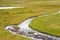 Meandering mountain creek running through tundra landscape