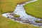 Meandering mountain creek running through tundra landscape