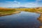 Meandering slow moving stream flows towards the mountains