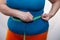 Measure the waist with a centimeter tape. Big size. The problem of excess weight. Full belly and folds. Hands of a woman dieting.