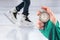 Measuring speed on skates with a stopwatch. hand with a stopwatch on the background of the legs of a man skating on an ice rink